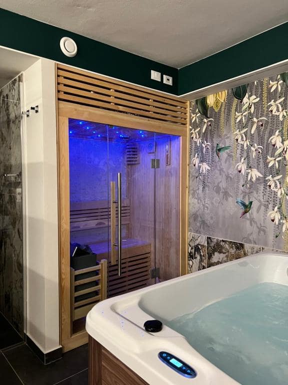 Sauna finlandese in cromoterapia blu profondo della SPA privata Marcello a Verona, vasca idromassaggio in primo piano e doccia in marmo venato accanto